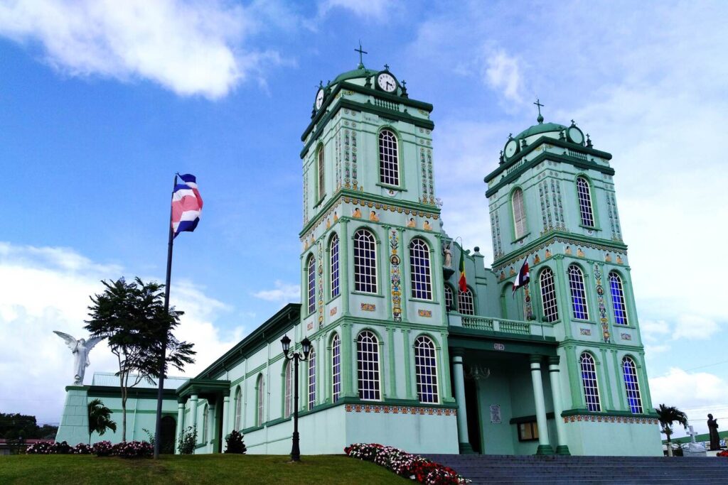 Green church in Sarchí with Costa Rican flag waving outside.