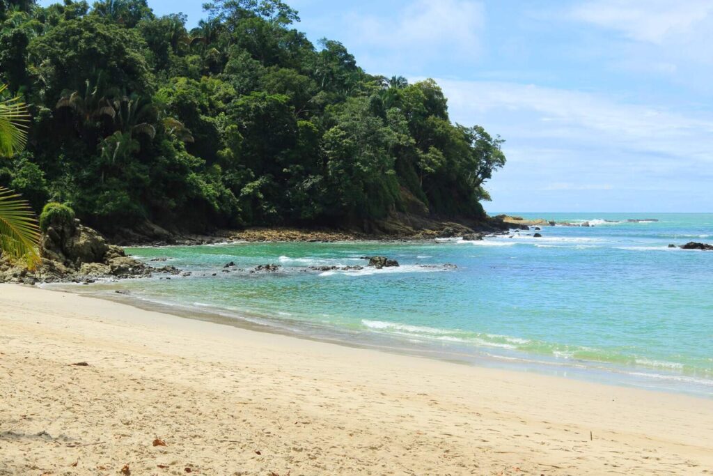 Sandy beach with turquoise water and lush forest in Manuel Antonio.