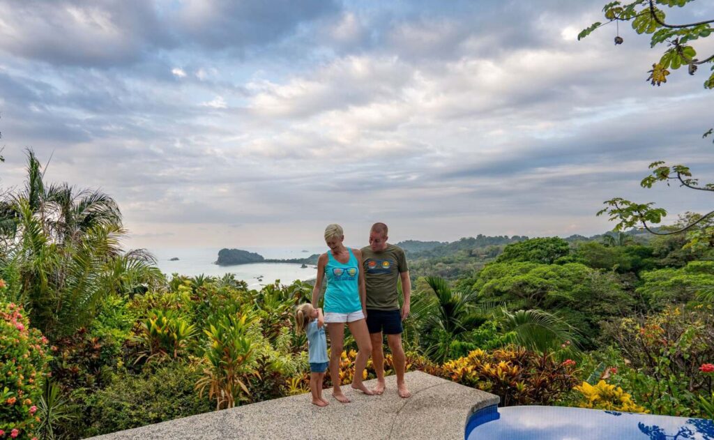 Couple with child by pool overlooking jungle and ocean